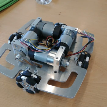 Untergestell des Roboters. Gut sichtbar sind die vier Motoren, die über einen Zahnriemen je ein Allseitenrad antreiben.
