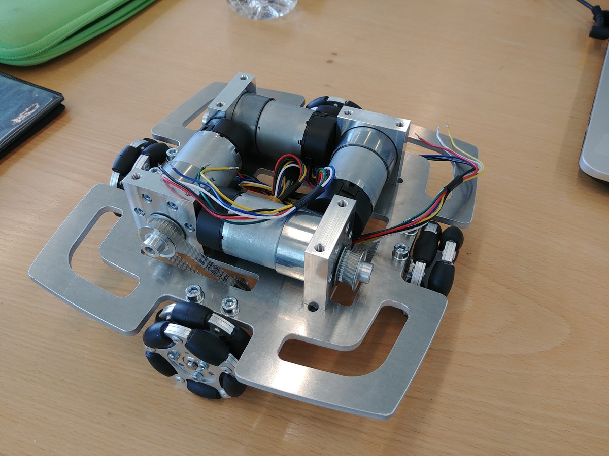 Untergestell des Roboters. Gut sichtbar sind die vier Motoren, die über einen Zahnriemen je ein Allseitenrad antreiben.